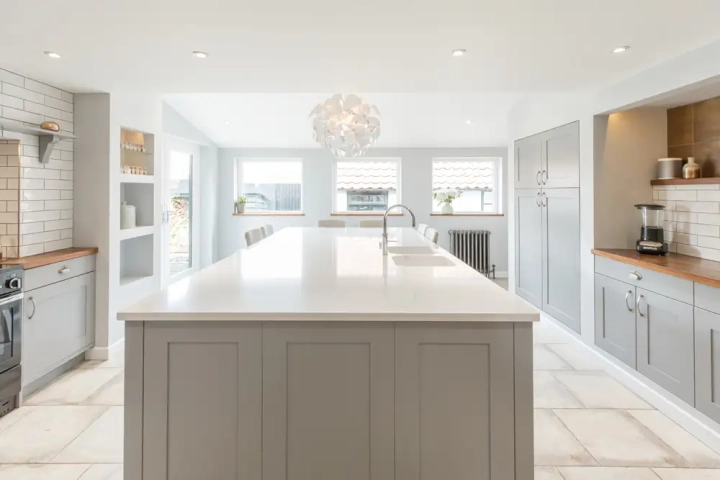 central kitchen island with white quartz worktop with designer pendant above