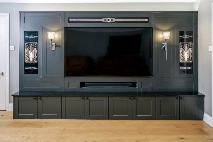 Bespoke dark media wall with lit inlaid glass art deco detailing 