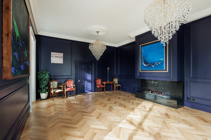 Art gallery with dark indigo walls with panelling and herringbone floor