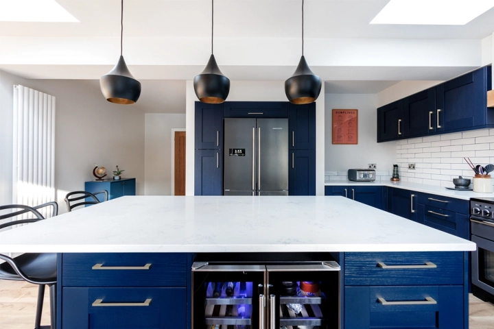 Modenr shake style kitchen with modern black pendants hanging above white centrl kitchen island