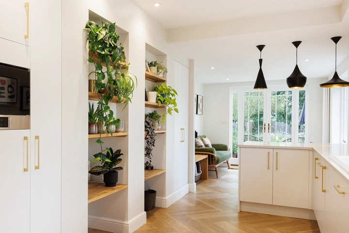 Mid century kitchen design with oak shleves with plants, stylish oak flooring and white cabinets and worktops