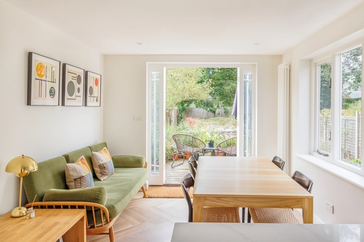 Dining room part of modern kitchen with oak table leading to patio doors open into garden