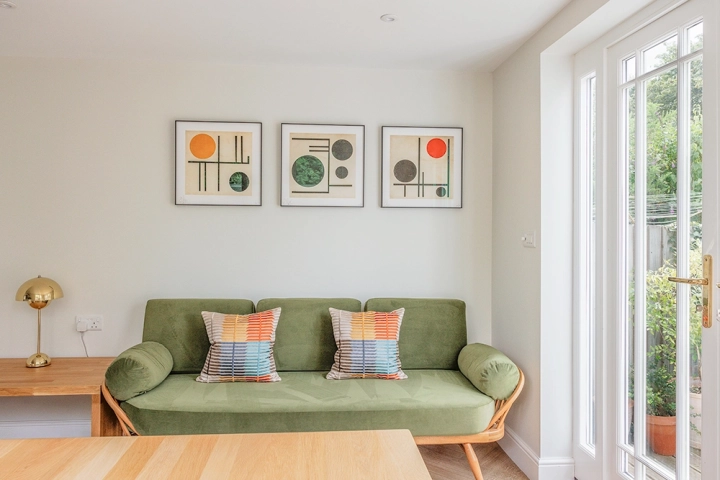 Modern green sofa with modern art on walls as part of kitchen diner
