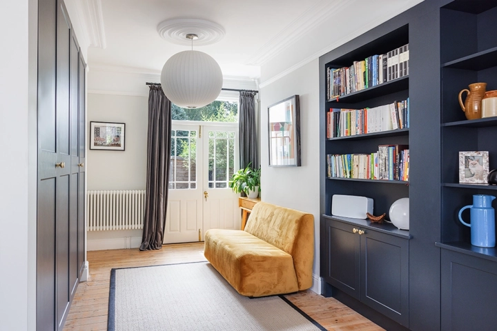 Contemporary lounge with in built cupboards and stylish furnishings with bespoke bookcase