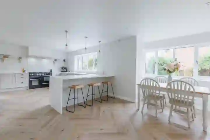 Spacious contemporary kitchen in Norwich featuring matte grey handleless cabinets, white quartz countertops, and a central island with integrated seating.