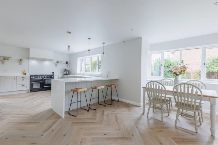 Spacious contemporary kitchen in Norwich featuring matte grey handleless cabinets, white quartz countertops, and a central island with integrated seating.
