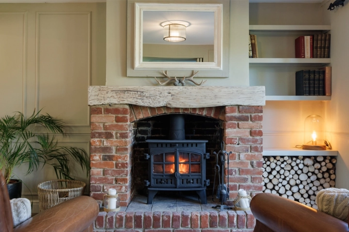 Country longue with exposed brick woodburner and bespoke built-in bookshelves