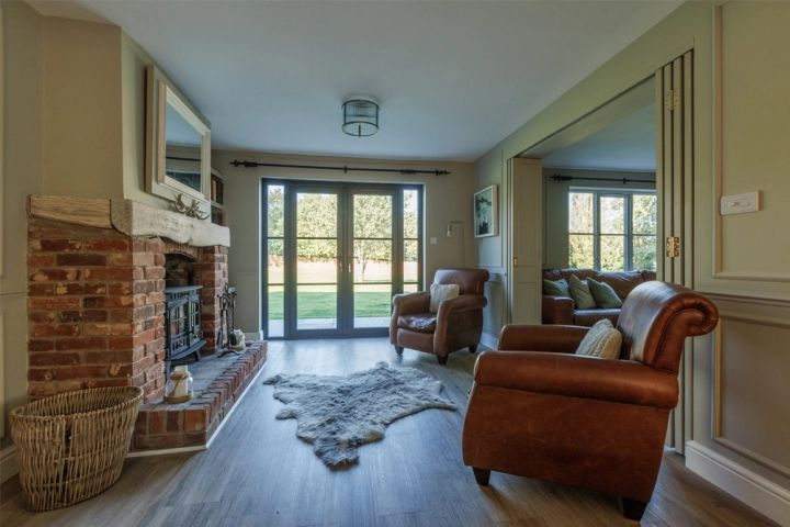 Country longue/diner with folding doors to a cinema room, exposed brick fireplace, and bi-fold doors