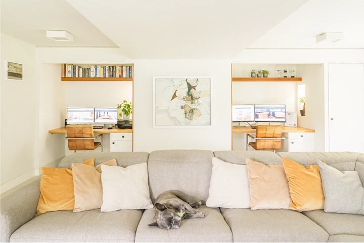 Home office with an L-shaped sofa before two built-in desks
