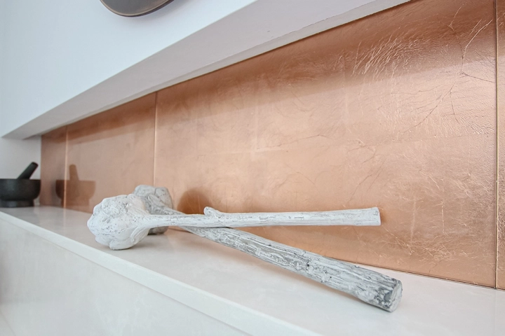 Close up of copper tile splashback and white quartz worktop