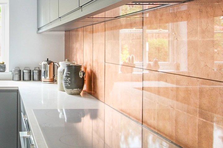 Close up of copper tile splashback and white quartz worktop