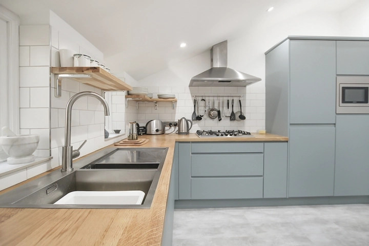 Contemporary kitchen with sky light, oak worktops and modern light blue doors, stainless steel sink and oven canopy
