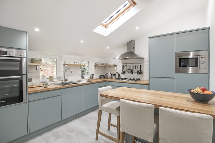 Contemporary kitchen with sky light, oak worktops and modern light blue doors, stainless steel sink and oven canopy