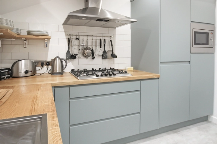Contemporary kitchen with sky light, oak worktops and modern light blue doors, stainless steel sink and oven canopy