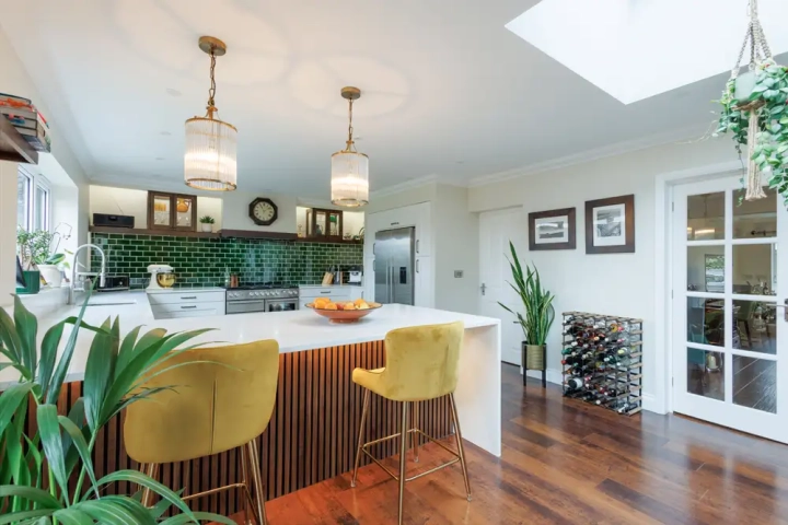 Open plan eclectic kitchen diner with green tile splashbacks