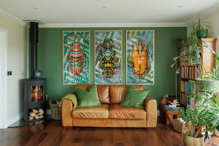 leather sofa next to wood burner with framed modern art pictures