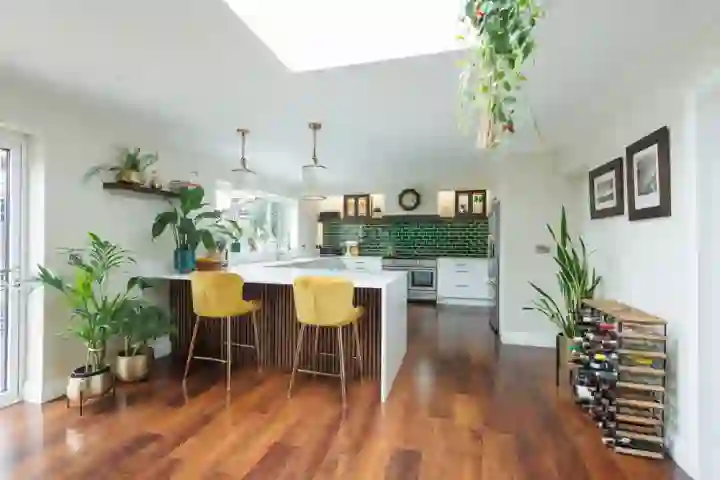 Stylish open plan kitchen diner with wooden flooring and white waterfall worktop