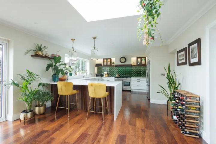 Stylish open plan kitchen diner with wooden flooring and white waterfall worktop