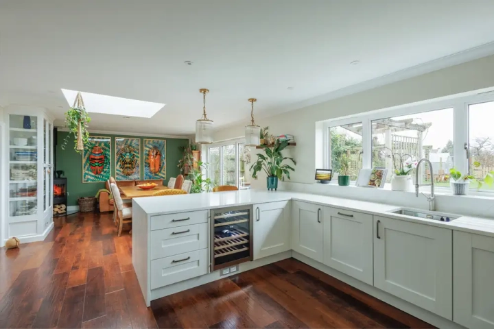Modern kitchen diner with breakfast bar, integrated wine fridge, shaker style white doors and modern handles